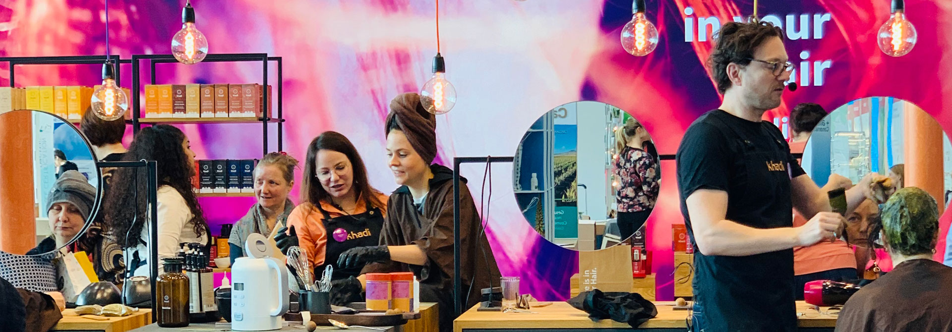 Mitarbeiterinnen und Kundinnen von khadi in Friseurschürzen, Färbekimono und Tunika